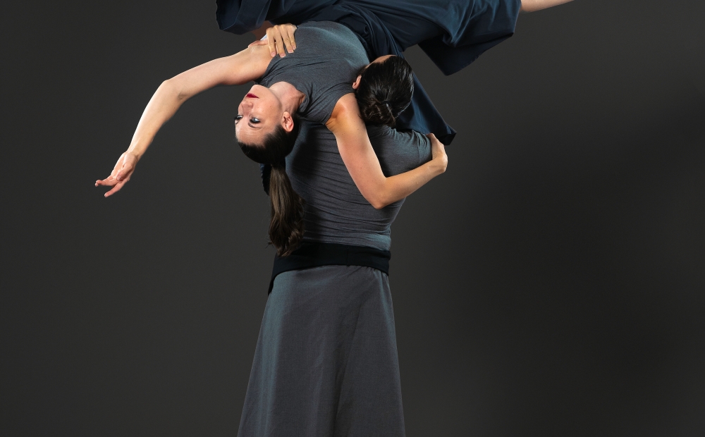 Image of two dancers, with one dancer posing on the shoulder of the other dancer.