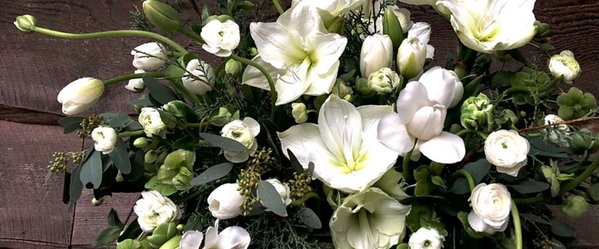 Detail of floral arrangement featuring white lilies, tulips and other blooms.